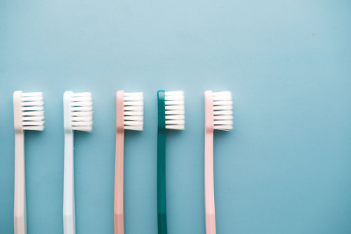 Cinco cepillos de dientes en fila con un fondo neutro 